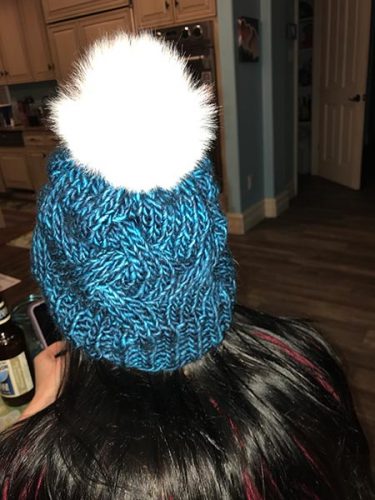 Kid 1 in a knitted blue hat with a pompom